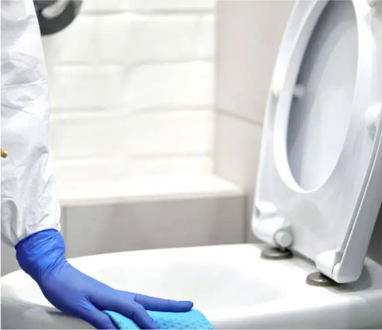 A person in blue gloves cleaning a toilet