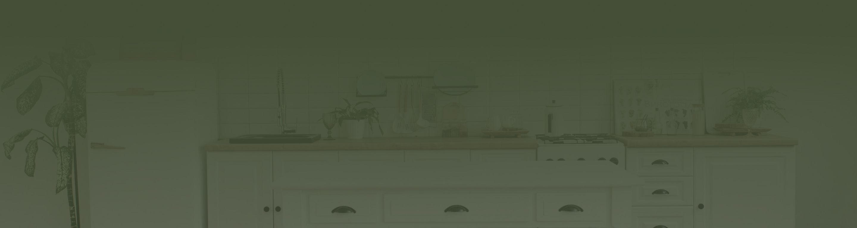 A kitchen with white cabinets and a green background