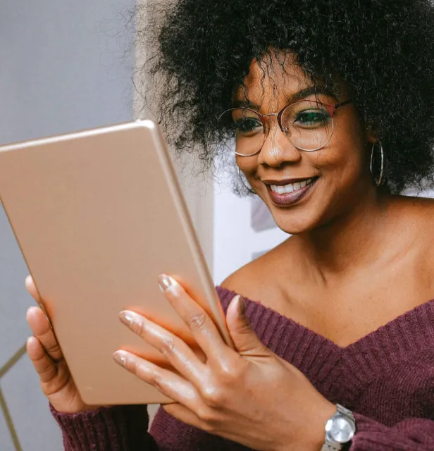 A woman wearing glasses is looking at a tablet