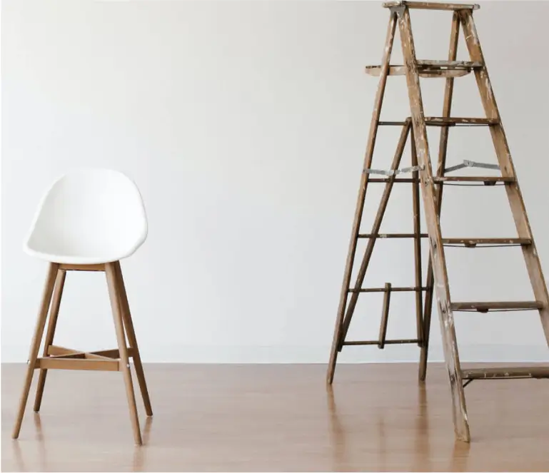 A ladder leaning against a wall next to a chair