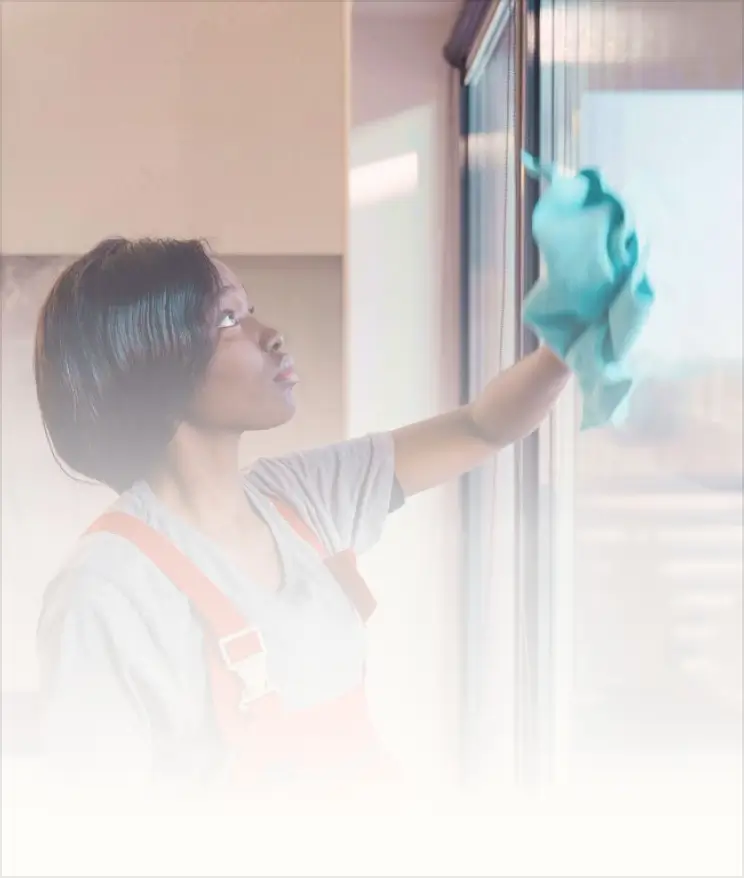 A woman is cleaning a window with a rag