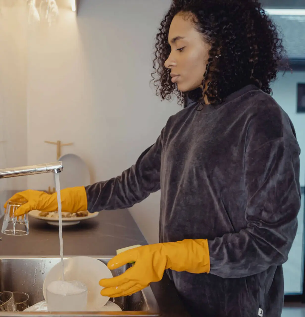 A woman washing dishes in a kitchen sink